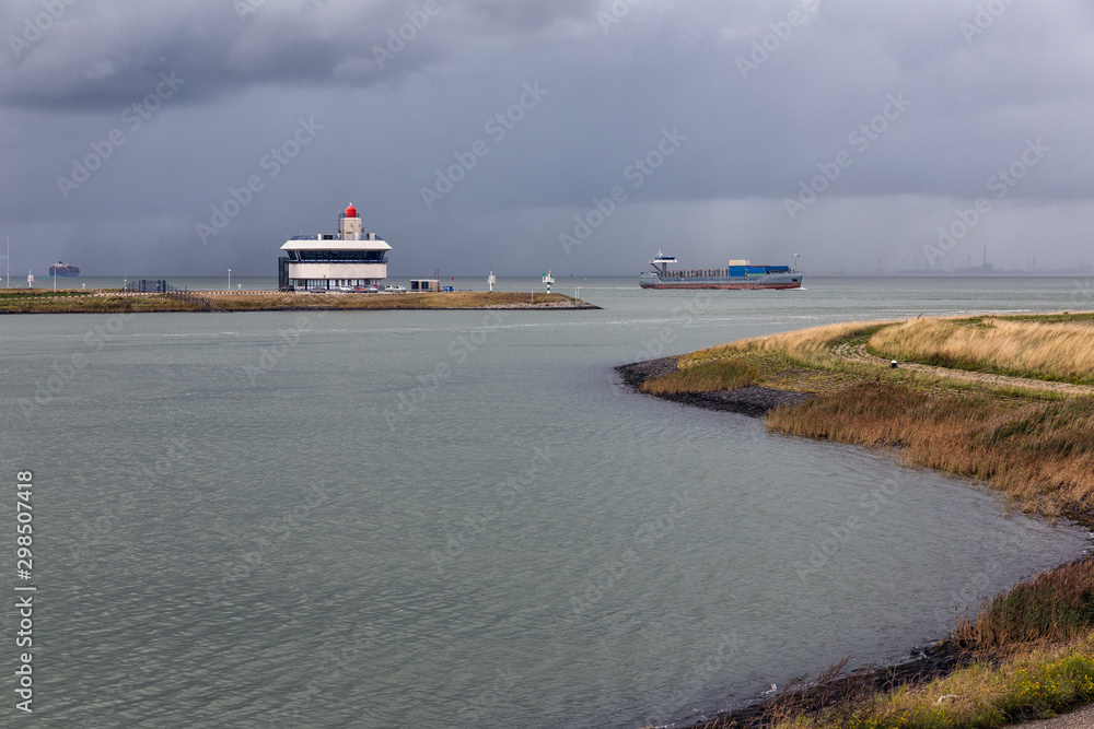 Entrance Dutch canal Terneuzen and cargo ship sailing river Schelde