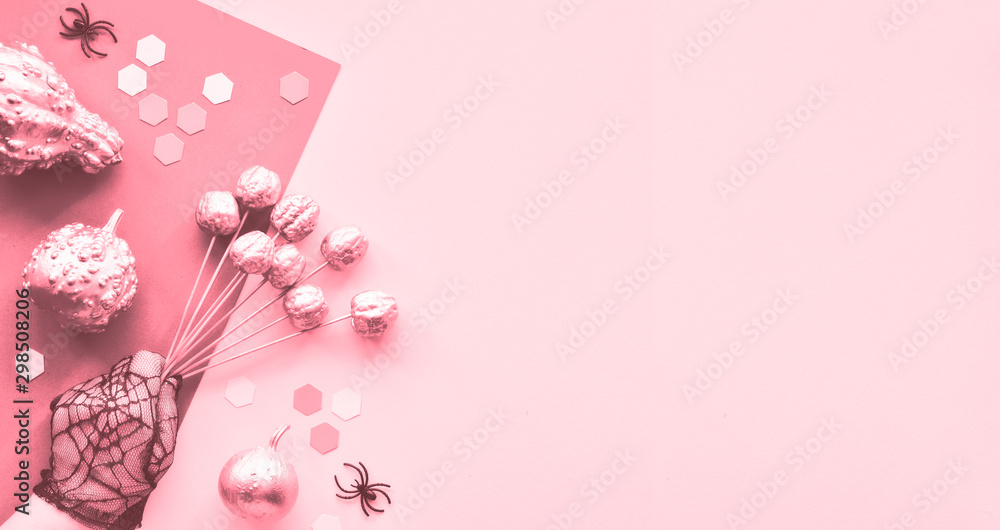 Creative paper craft Halloween flat lay, monochrome pink flat lay on split paper with hand in mesh glove, pumpkins, eyes, spiders and hexagons. Panoramic image, copy-space.