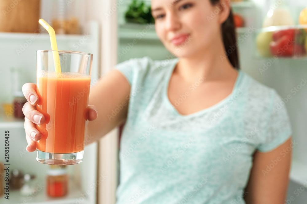 Body Care. Chubby girl standing in kitchen near fridge with glass of juice close-up blurred background Body Care. Chubby girl standing in kitchen near fridge with glass of juice close-up blurred background