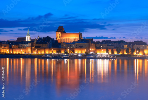 Torun old town in Poland, UNESCO world heritage site, with illumination, reflected in Vistula river at beautiful evening.