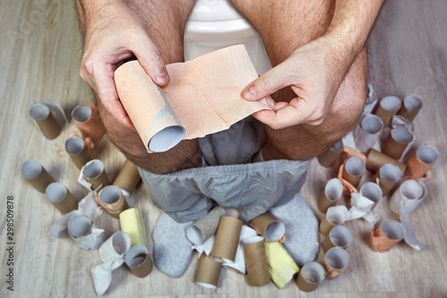 Принти на полотні One man sits on a WC with toilet paper in hands.