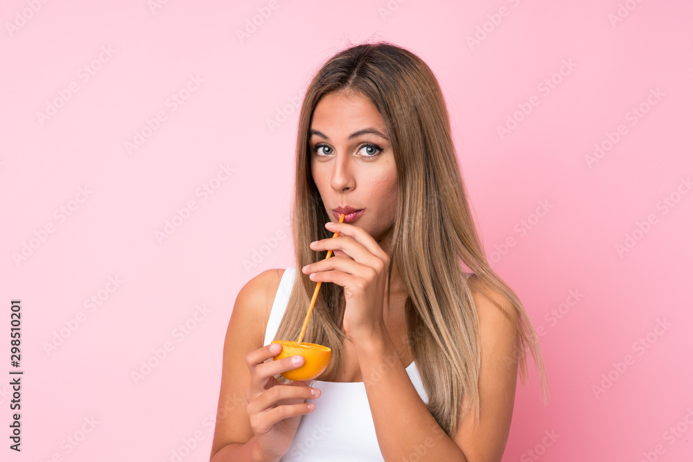 Young blonde woman over isolated background holding an orange Young blonde woman over isolated background holding an orange