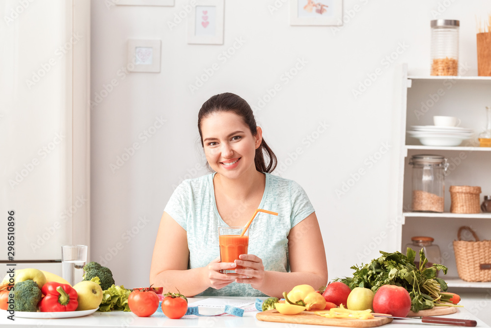 Body Care. Chubby girl sitting at kitchen table drinking detox juice smiling happy Body Care. Chubby girl sitting at kitchen table drinking detox juice smiling happy