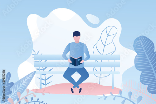 Handsome man reading a book or magazine while sitting on a bench