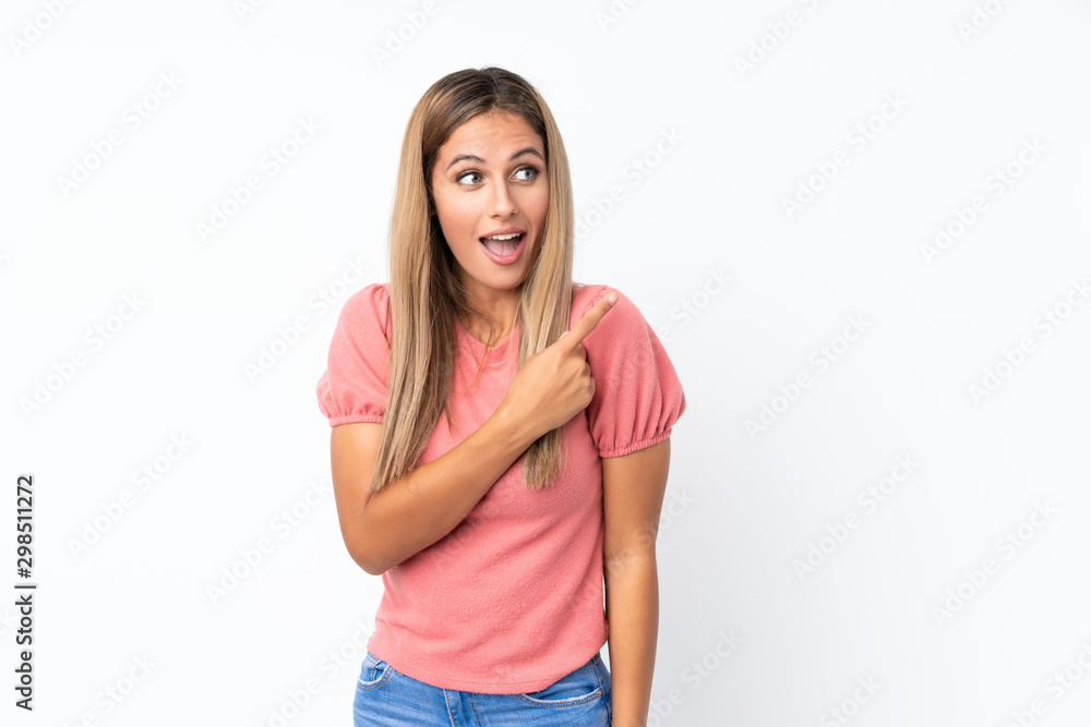 Young blonde woman over isolated white background surprised and pointing side Young blonde woman over isolated white background surprised and pointing side