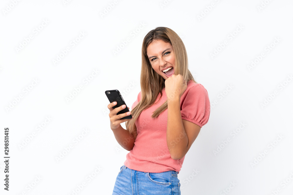 Young blonde woman over isolated white background with phone in victory position Young blonde woman over isolated white background with phone in victory position