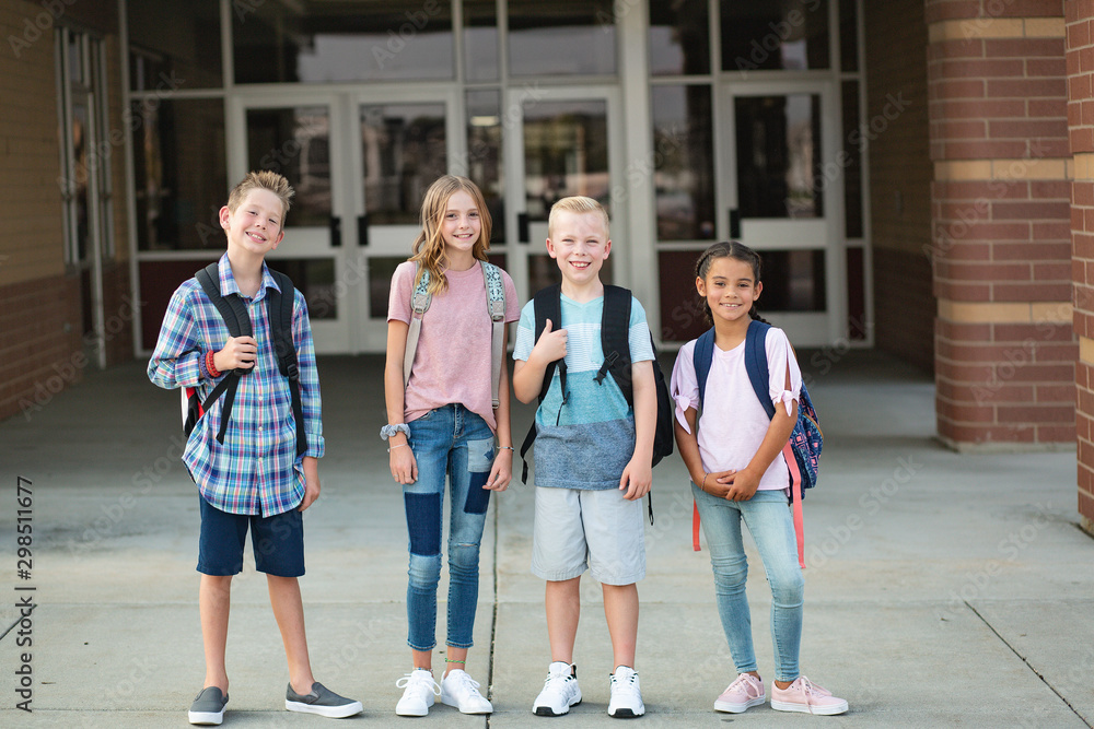 Group of Elementary school students standing in front of their school. Smiling and hanging out together after school. Group of Elementary school students standing in front of their school. Smiling and hanging out together after school.