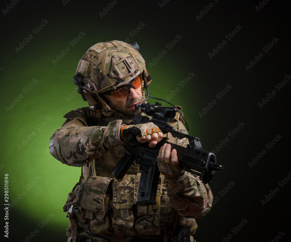 a male soldier in military clothes with a weapon on a dark background a male soldier in military clothes with a weapon on a dark background