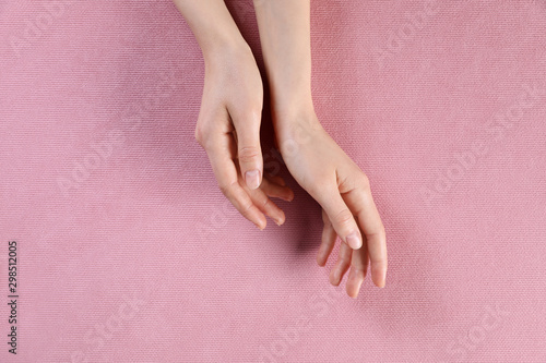 Woman with beautiful hands on pink fabric  top view
