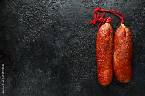 traditional Balearic raw cured meat sobrassada sausage made from ground pork, paprika and spices on rustic black background photo