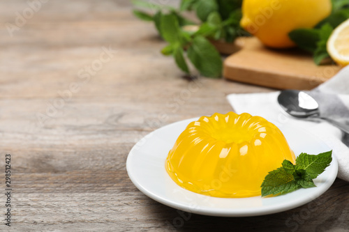 Delicious fresh yellow jelly with mint on wooden table. Space for text photo