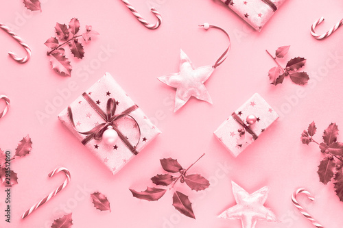 Fototapeta Naklejka Na Ścianę i Meble -  Festive monochrome pink Christmas background with pink gift boxes, stripy candy canes, trinkets and decorative stars, geometric creative flat lay