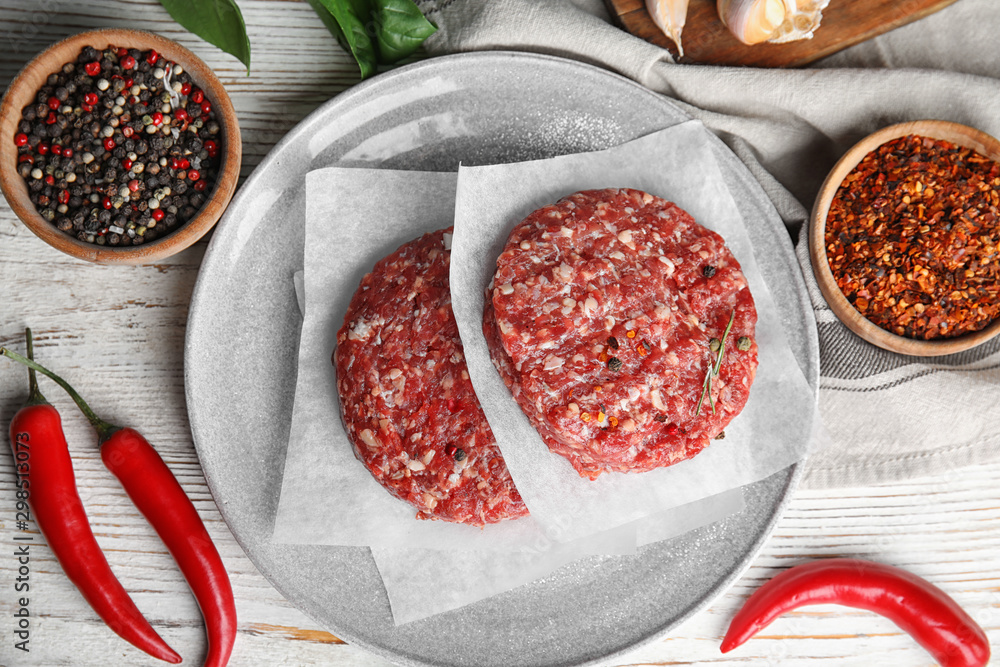 Flat lay composition with raw meat cutlets for burger on white wooden table Flat lay composition with raw meat cutlets for burger on white wooden table