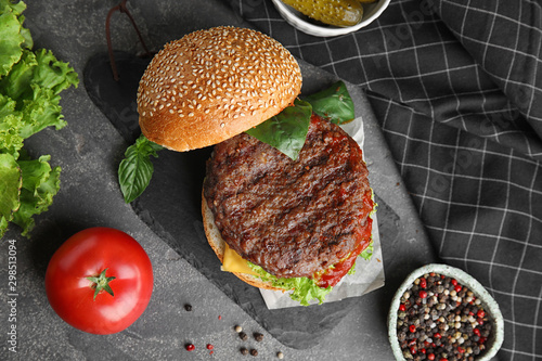 Delicious burger with meat cutlet on grey table, flat lay