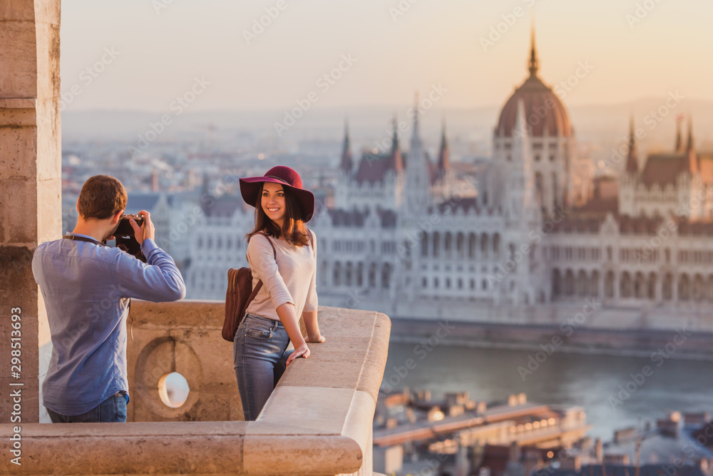Obraz premium Młoda para robi sobie zdjęcia w punkcie widokowym z Baszty Rybackiej w Budapeszcie o wschodzie słońca.
