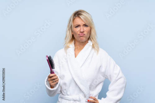 Young woman in a bathrobe with hair comb with sad expression