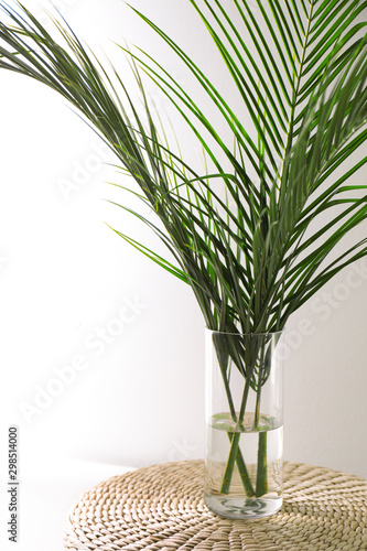 Green tropical leaves in vase on table. Modern decor for stylish interior