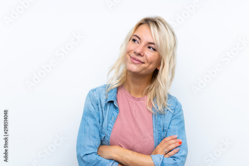 Young blonde woman over isolated white background looking up while smiling
