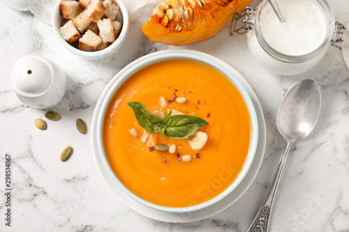 Delicious pumpkin soup in bowl on marble table, flat lay