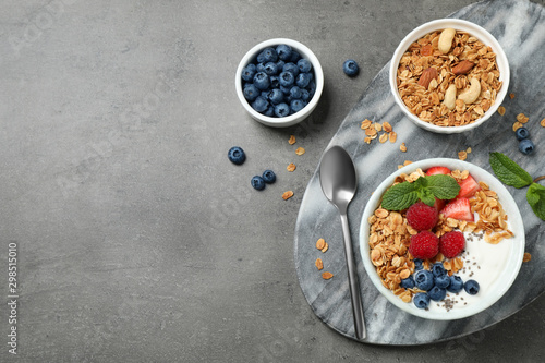 Healthy homemade granola with yogurt on grey table, flat lay. Space for text