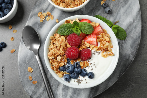 Tasty homemade granola with yogurt and berries on grey table, flat lay. Healthy breakfast