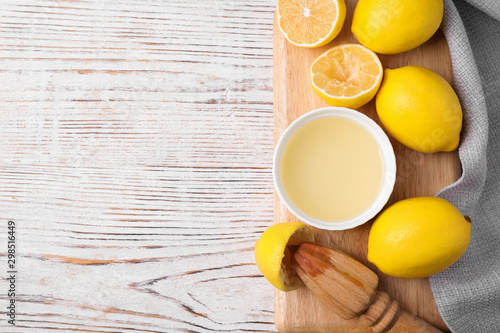 Freshly squeezed lemon juice and squeezer on wooden table, top view. Space for text