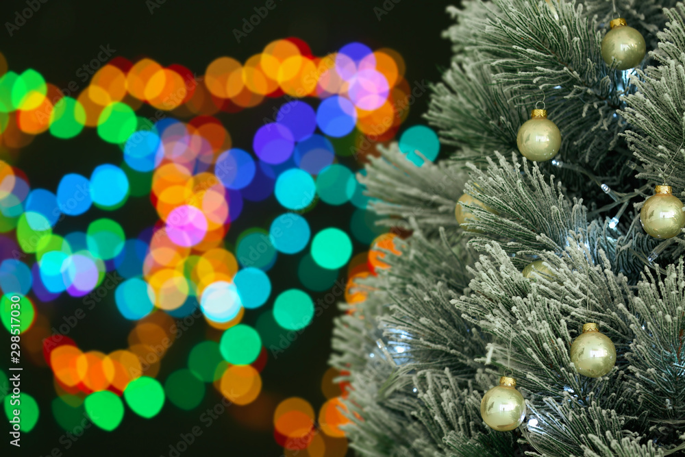 Decorated Christmas tree against blurred festive lights, closeup. Space for text