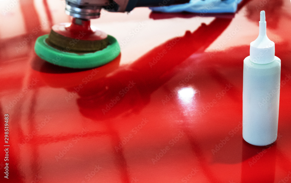 Tools and means for polishing. Glossy red surface. Copy space. White bottle with polish in the foreground. Noise, film grain. Tools and means for polishing. Glossy red surface. Copy space. White bottle with polish in the foreground. Noise, film grain.