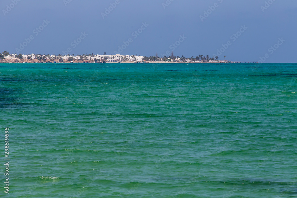 Turquoise and warm waters in Tunisia with a view of an island.