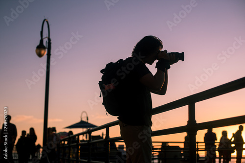 Canvas Print A young male photographer photographs the sunset from the Santa Monica Pier