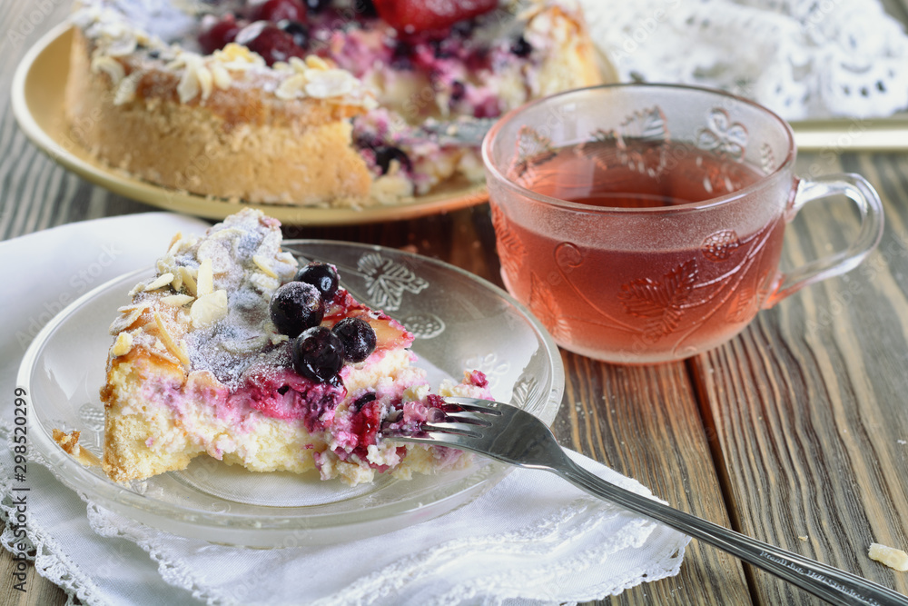 Φωτογραφία A piece of delicious berry tarte (flan) next to a cup of fragrant tea and whole