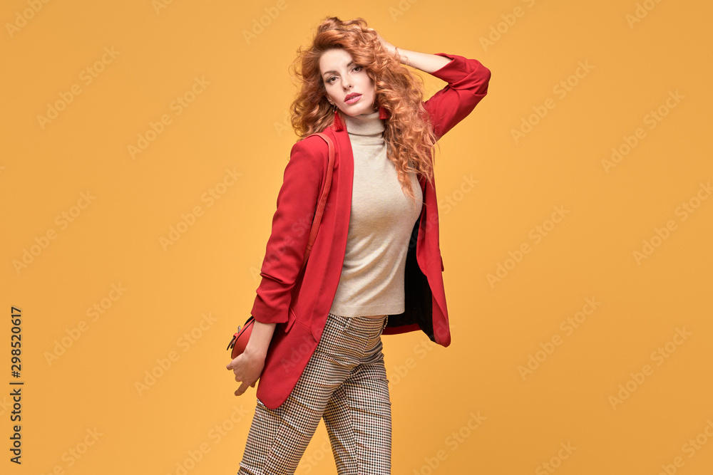 Fashion. Beautiful woman in autumn red jacket, trendy curly hair, make up. Adorable well dressed redhead girl on orange. Gorgeous fashionable lady in red, hairstyle, makeup. Creative beauty shot Fashion. Beautiful woman in autumn red jacket, trendy curly hair, make up. Adorable well dressed redhead girl on orange. Gorgeous fashionable lady in red, hairstyle, makeup. Creative beauty shot