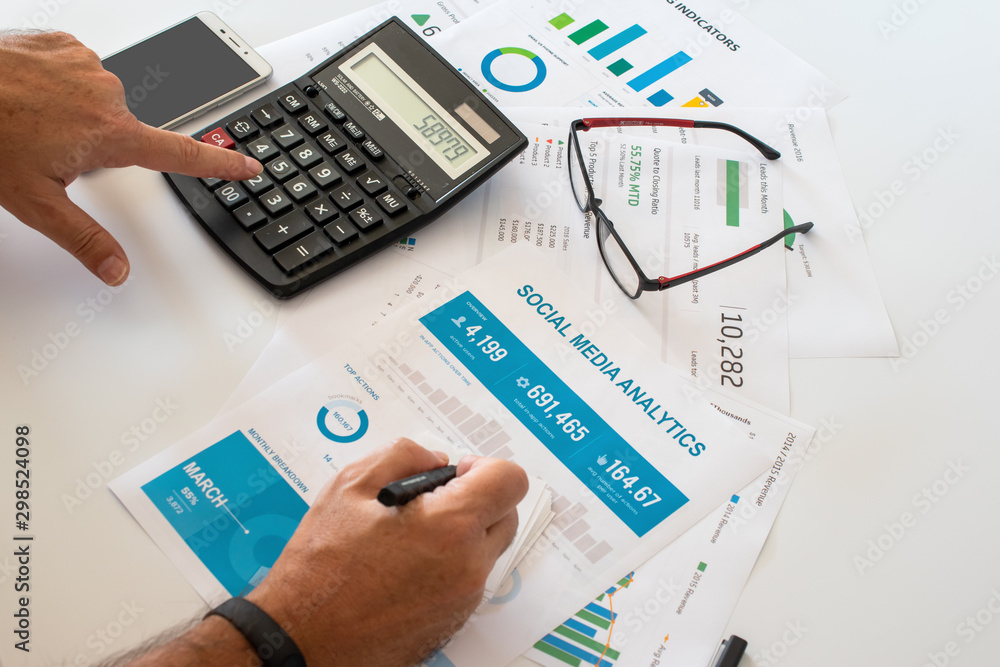 Businessman calculating social media analytics on office desk Businessman calculating social media analytics on office desk