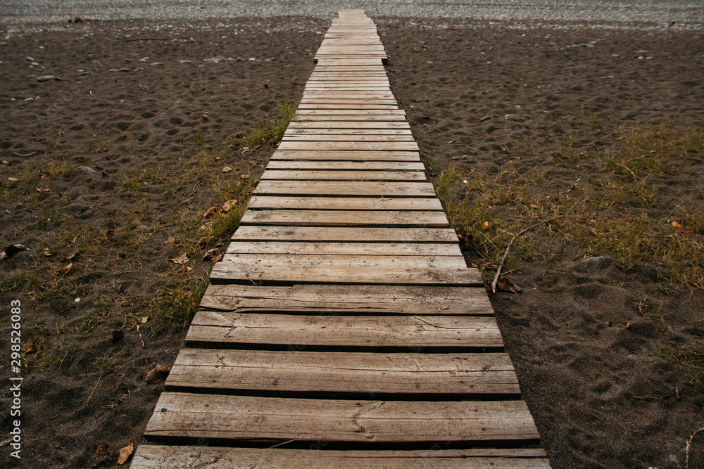 Wooden path on the sandy beach. Beach boardwalk with sand texture background Wooden path on the sandy beach. Beach boardwalk with sand texture background