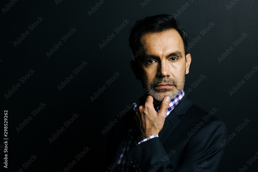 Portrait of a serious man in checkered shirt and jacket, isolated on black studio background Portrait of a serious man in checkered shirt and jacket, isolated on black studio background