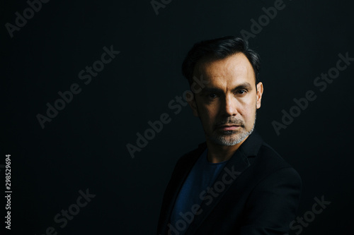 Portrait of a mature man looking at camera, isolated on black studio background