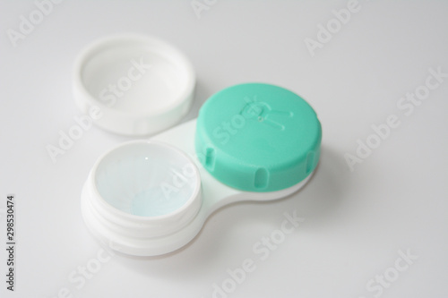 container for soft contact lenses and lens on light background