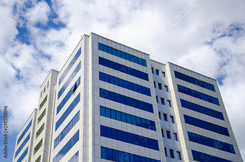 Architectural background, fragment of a modern office building against blue sky with clouds