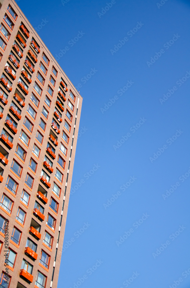 Architectural background of a fragment of orange modern residential building against the clear blue sky