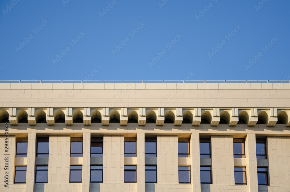 Architectural background, facade of a modern building with a geometric pattern of decorative elements against blue sky Architectural background, facade of a modern building with a geometric pattern of decorative elements against blue sky