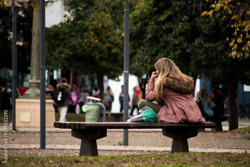 Mujer esperando sentada en el banco de la plaza.