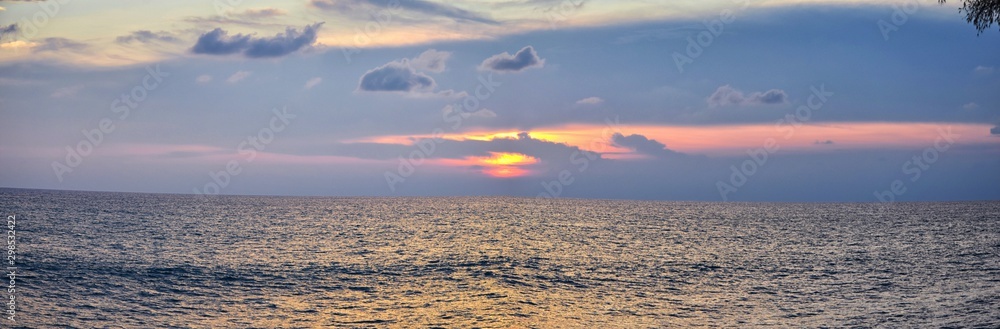 Phuket beach sunset, colorful cloudy twilight sky reflecting on the sand gazing at the Indian Ocean, Thailand, Asia.
