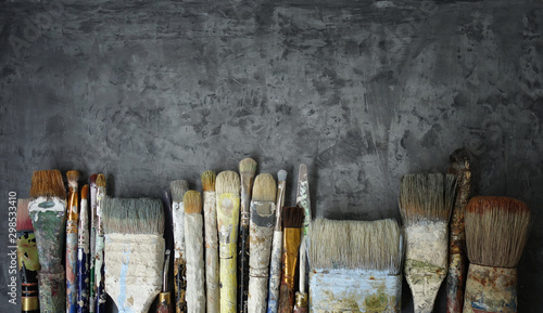 row of old artist paintbrushes on a dark gray decorative stucco surface