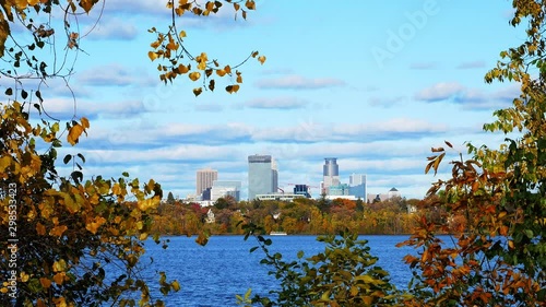 Skyline of downtown Minneapolis, Minnesota from the south shore of Lake Bde Maka Ska or Lake Calhoun on a beautiful autmn afternoon with colorful leaves in foreground and zoom in. photo