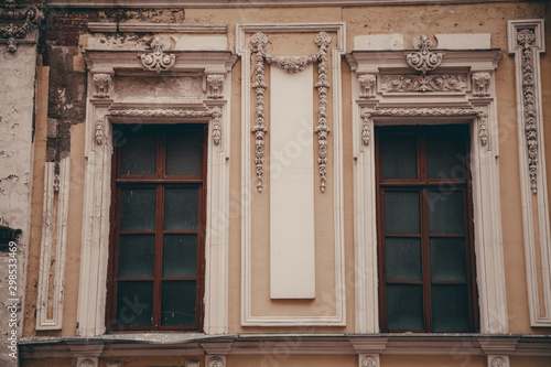 two very old windows on the yellow wall with nobody.