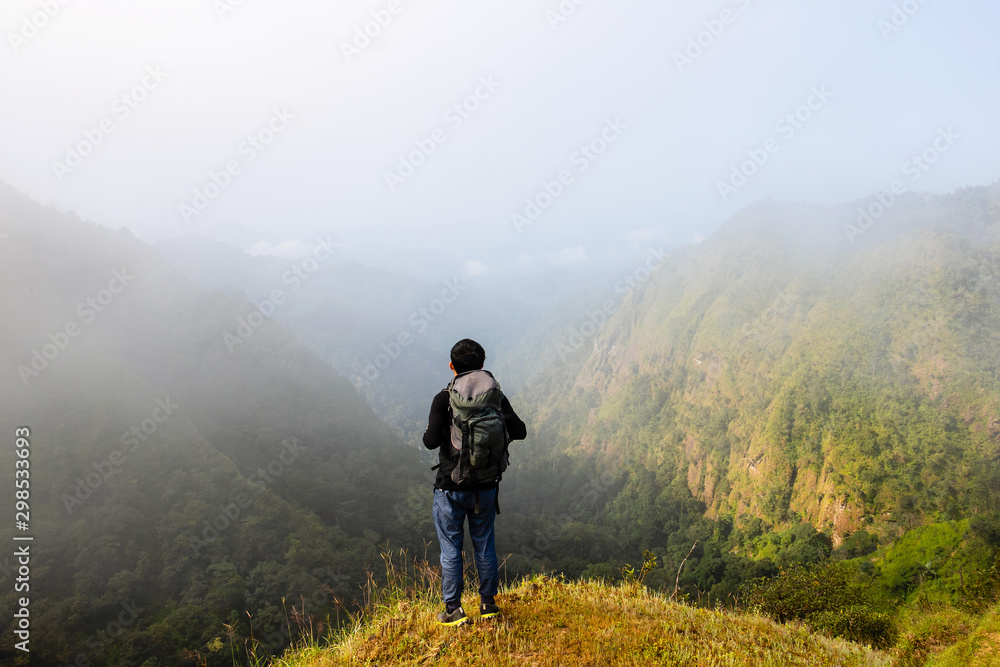 A backpack man standing on cliff and see over view in nature.Tourist  enjoying fresh air. A man enjoying free happiness in beautiful Thailand landscape.