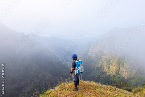 A backpack man standing on cliff and see over view in nature.Tourist enjoying fresh air. A man enjoying free happiness in beautiful Thailand landscape.