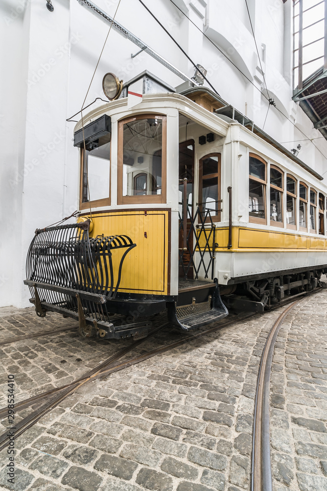 Perspective view of the old yellow tram with wooden windows and open driver cab. Vintage portugal city transport