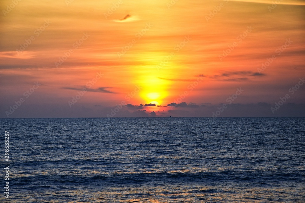 Phuket beach sunset, colorful cloudy twilight sky reflecting on the sand gazing at the Indian Ocean, Thailand, Asia.