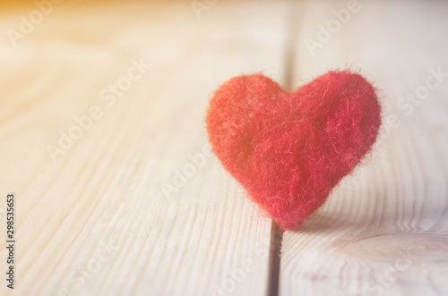 red heart made of wool on wooden background  a symbol of love  bright sun background